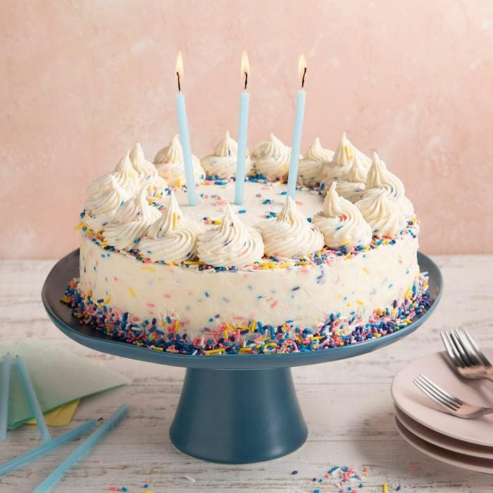 Festive layer cake with chocolate frosting and lit birthday candles