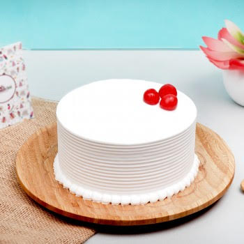 Rustic white cake adorned with fresh raspberries and a light dusting